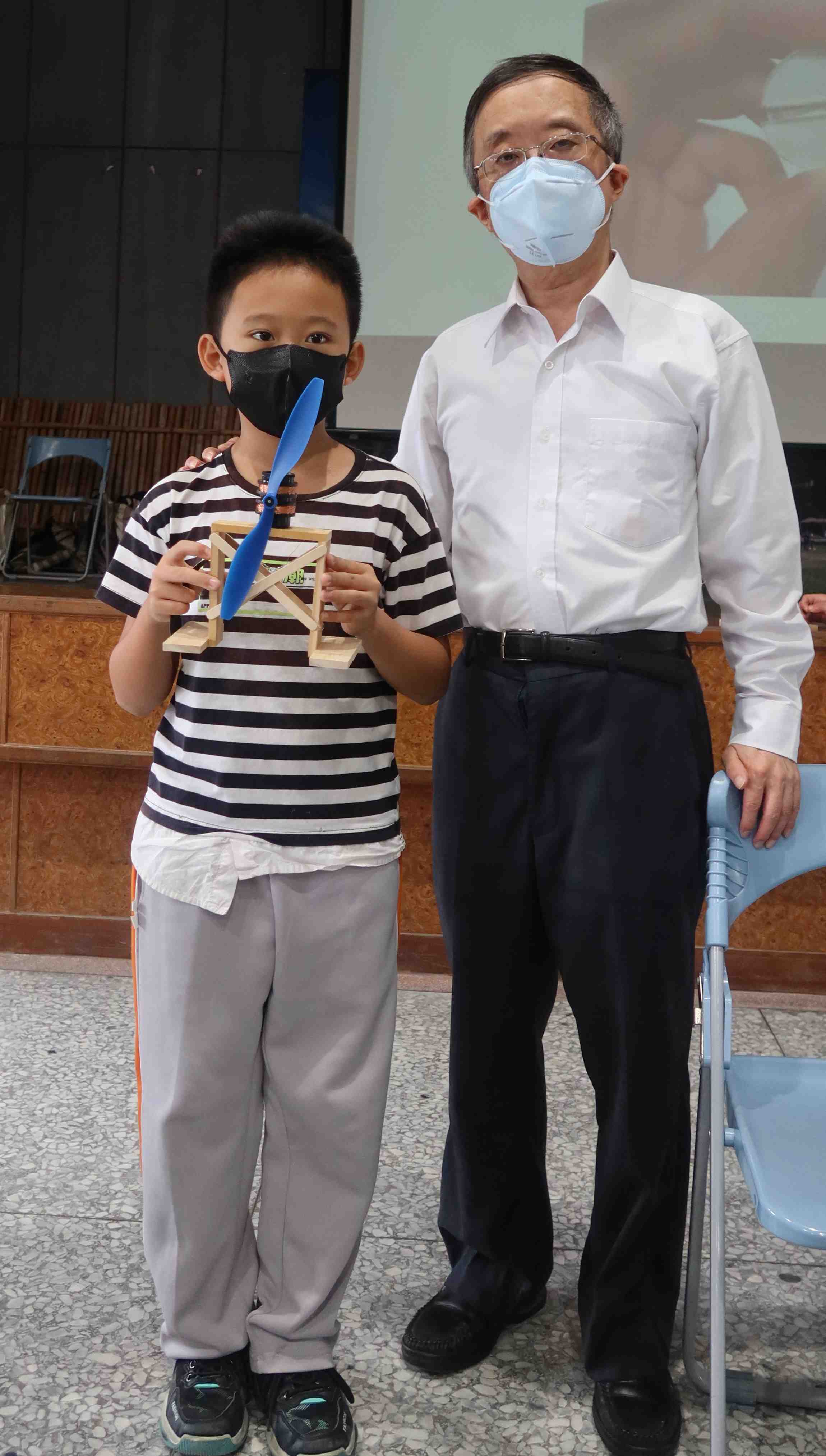國小學童手持自製的風力發電機與周祥順老師合影.
